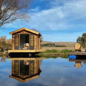 off grid tiny House on wheels and trailer beside a lake